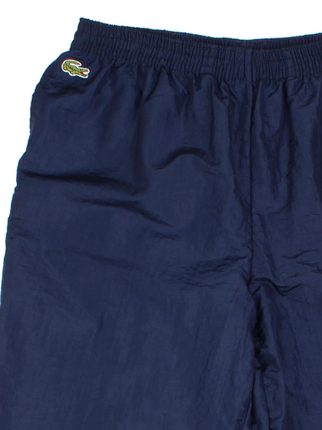 Vintage Lacoste Shell Pants in a blue colourway with pockets, elasticated waist with drawstring, cotton lining and the logo embroidered on the front.