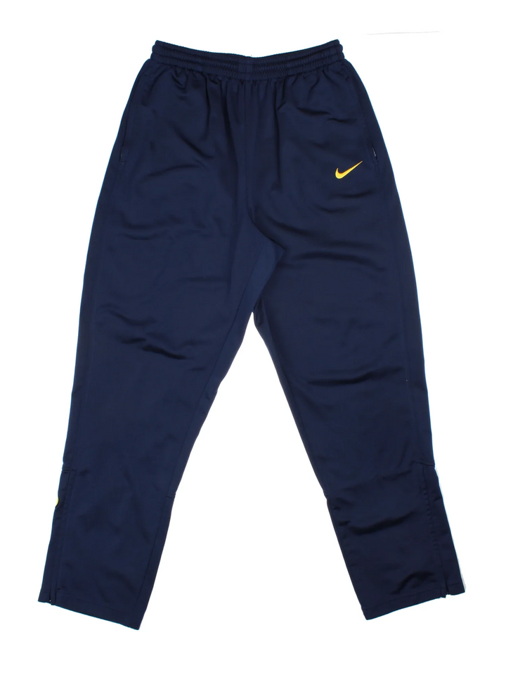 Nike Tracksuit Bottoms in a blue colourway with zip up side pockets, elasticated waist with drawstring, and the swoosh logo embroidered on the front and back.