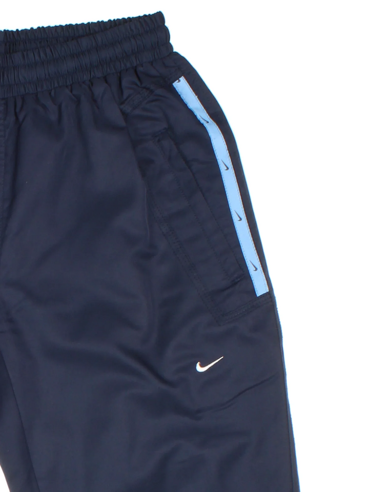 Y2K Nike Tracksuit Bottoms in a blue colourway with pockets, elasticated waist with drawstring, and has the logo embroidered on the front.
