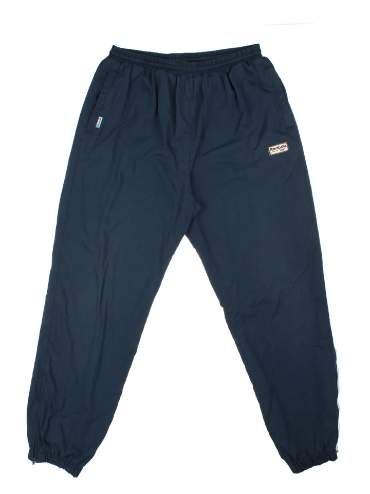 Reebok Tracksuit Bottoms in a blue colourway with pockets, cotton lining, elasticated waist with drawstring, and has the logo embroidered on the front.