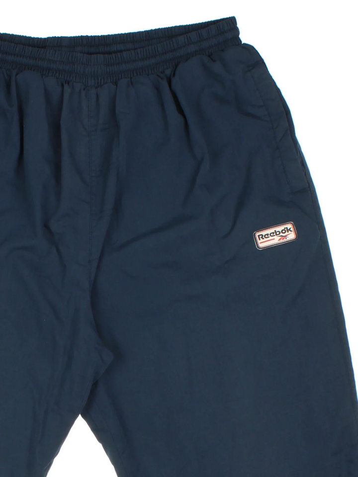 Reebok Tracksuit Bottoms in a blue colourway with pockets, cotton lining, elasticated waist with drawstring, and has the logo embroidered on the front.