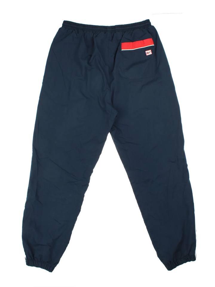 Reebok Tracksuit Bottoms in a blue colourway with pockets, cotton lining, elasticated waist with drawstring, and has the logo embroidered on the front.