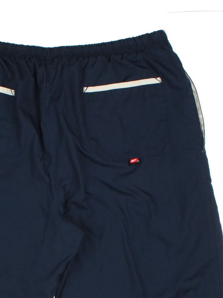 Nike Tracksuit Bottoms in a blue colourway with pockets, elasticated waist with drawstring, cotton lining, and the swoosh logo embroidered on the front.