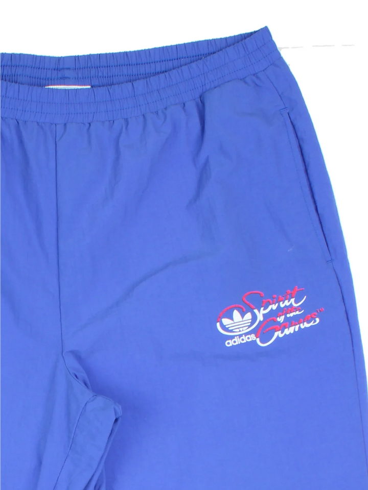 Vintage 80's Adidas Olympics Spirit Of The Games Tracksuit Bottoms in a blue colourway with pockets, elasticated waist, and the logo printed on the front.