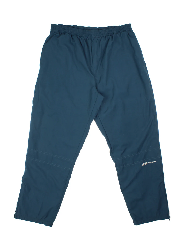 Reebok Tracksuit Bottoms in a blue colourway with pockets, elasticated waist, and the logo embroidered on the front.