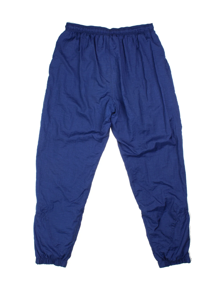 Vintage 90's Nike Shell Tracksuit Bottoms in blue colourway, has pockets, elasticated waist with drawstring, cotton blend lining, and the logo embroidered on the front.