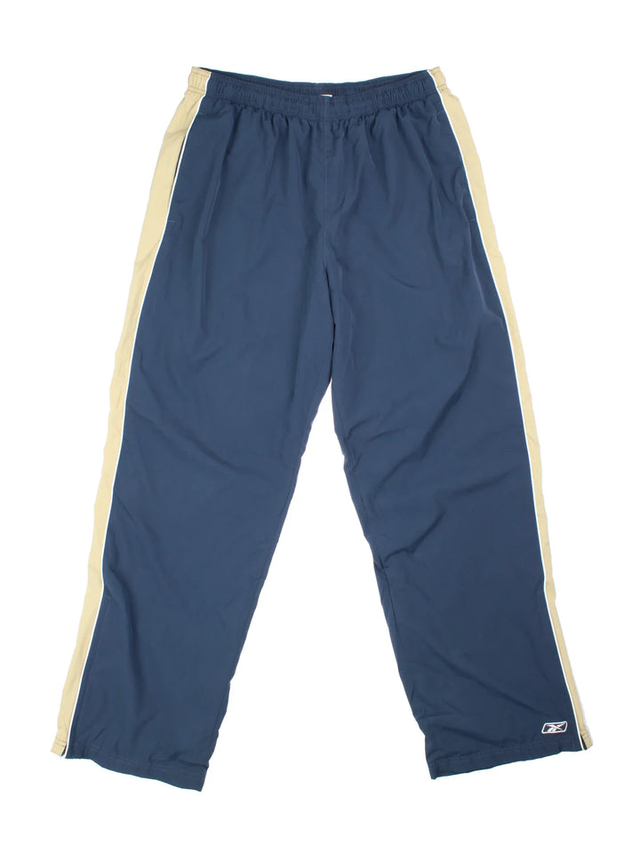 Reebok Tracksuit Bottoms in blue colourway, has pockets, elasticated waist with drawstring, cotton blend lining, and the logo embroidered on the front by the hem.