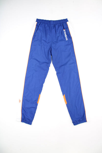 Vintage Reebok tracksuit bottoms in blue, orange and white. Features embroidered logo and drawstring waist.