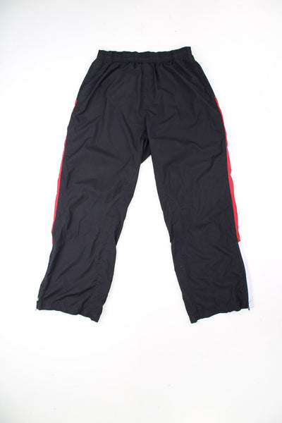 Black, red and white Reebok tracksuit bottoms with elasticated drawstring waist. Features embroidered logo.