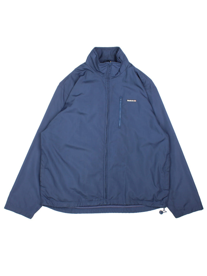 Vintage Reebok Windbreaker in a blue colourway. Zip up fastening ,with side/chest pockets. Jersey lining and front logo.
