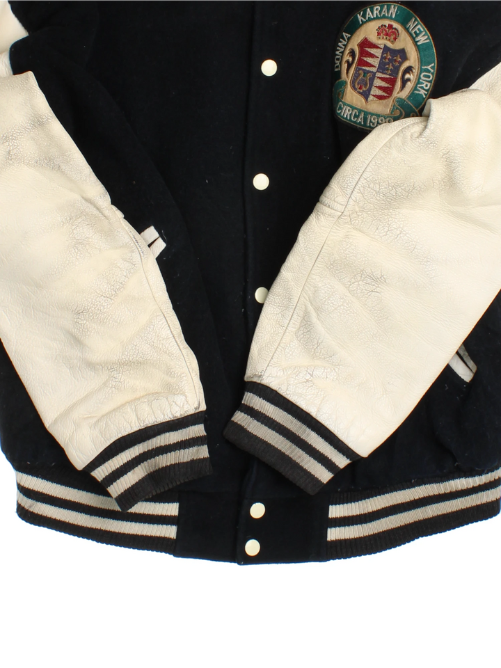 Vintage 90's DKNY black and white varsity jacket with wool body and leather sleeves, features embroidered badges and large spell-out motif on the back 