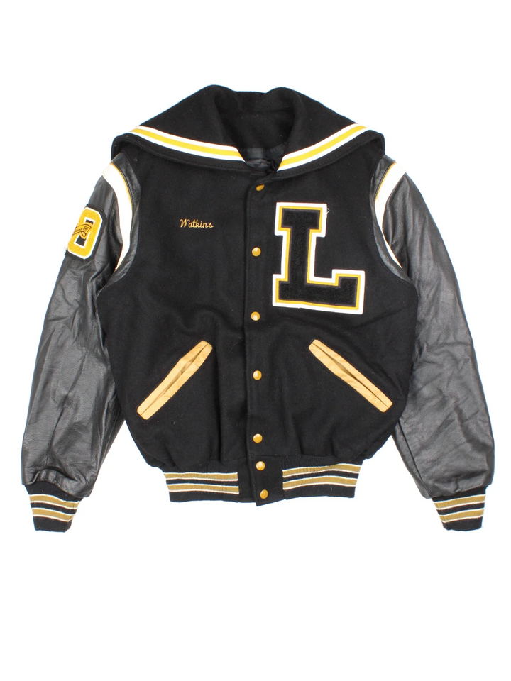 Vintage De Long Varsity Jacket in a black/yellow colourway. Features embroidered badges on front and embroidered spell-out on the back, contrasts cuffs and collars, buttons up and has side pockets. Insulated with a contrast lining.
