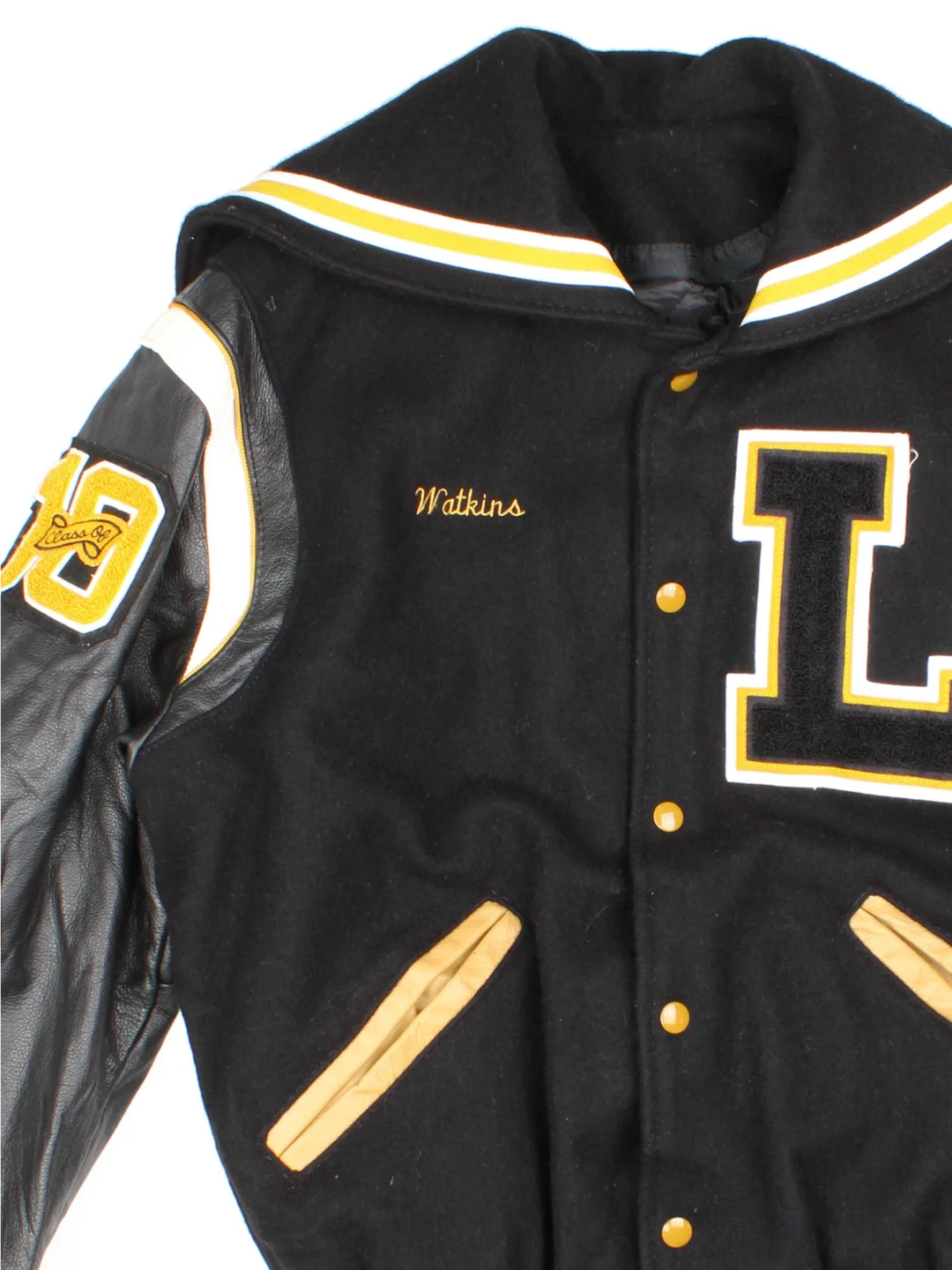 Vintage De Long Varsity Jacket in a black/yellow colourway. Features embroidered badges on front and embroidered spell-out on the back, contrasts cuffs and collars, buttons up and has side pockets. Insulated with a contrast lining.