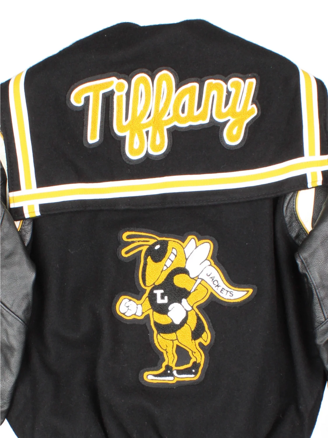 Vintage De Long Varsity Jacket in a black/yellow colourway. Features embroidered badges on front and embroidered spell-out on the back, contrasts cuffs and collars, buttons up and has side pockets. Insulated with a contrast lining.