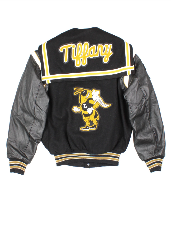 Vintage De Long Varsity Jacket in a black/yellow colourway. Features embroidered badges on front and embroidered spell-out on the back, contrasts cuffs and collars, buttons up and has side pockets. Insulated with a contrast lining.