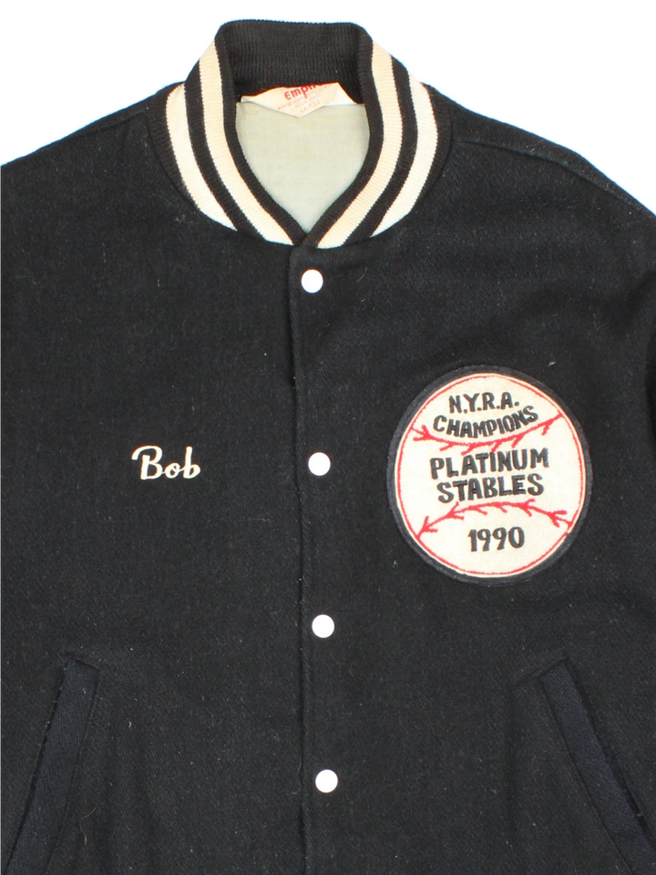 Vintage N.Y.R.A Champions Varsity Jacket in a black/white colourway.  Features embroidered badges on front, contrasts cuffs and collars, buttons up and has side pockets. Insulated with a contrast lining.