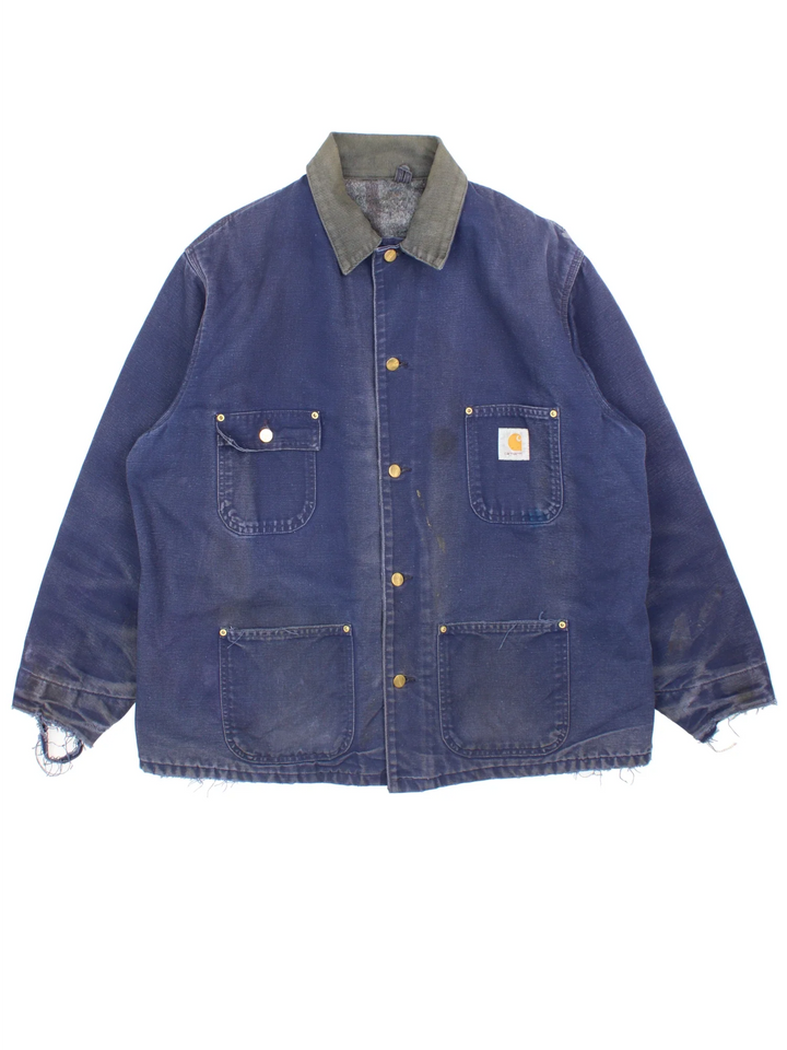 Vintage Carhartt Chore Jacket in a blue colourway with a contrast corduroy collar. Buttons up and has multiple pockets, insulated with a blanket lining, and has the logos embroidered on the front.