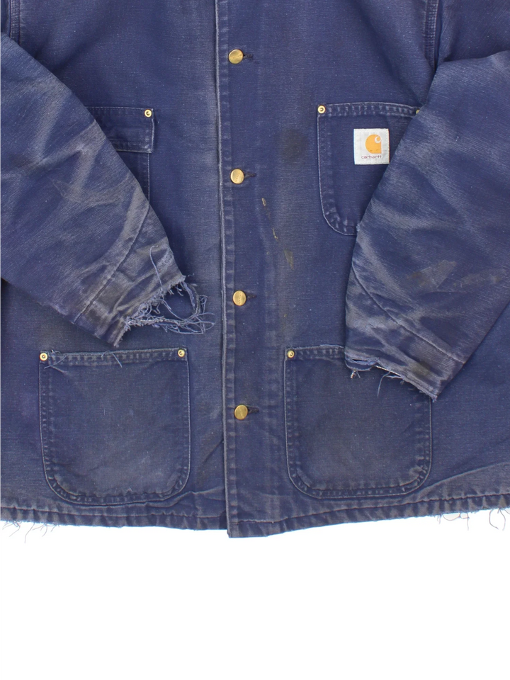 Vintage Carhartt Chore Jacket in a blue colourway with a contrast corduroy collar. Buttons up and has multiple pockets, insulated with a blanket lining, and has the logos embroidered on the front.