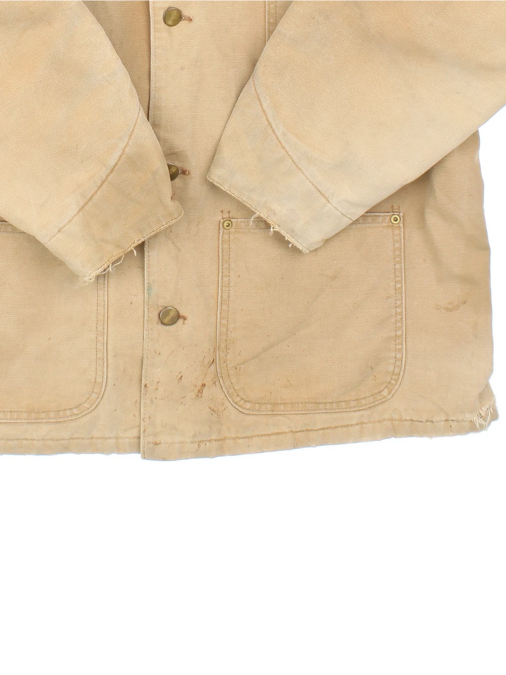 Vintage Carhartt Chore Jacket in a tan colourway. Buttons up and has multiple pockets, insulated with a blanket lining, and has the logos embroidered on the front.