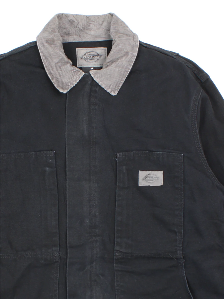 Dickies Chore Work Jacket in a black colourway with a grey corduroy collar. Zip up closure and has multiple pockets, insulated lining, and has the logo embroidered on the front.