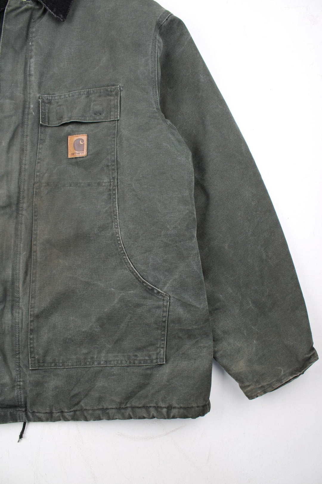 Carhartt Arctic Jacket in a green colourway with a black corduroy collar. Zips up and has multiple pockets, insulated with a quilted lining, and has the logo embroidered on the front.