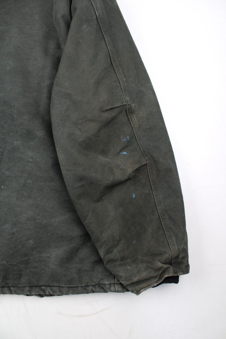 Carhartt Arctic Jacket in a green colourway with a black corduroy collar. Zips up and has multiple pockets, insulated with a quilted lining, and has the logo embroidered on the front.