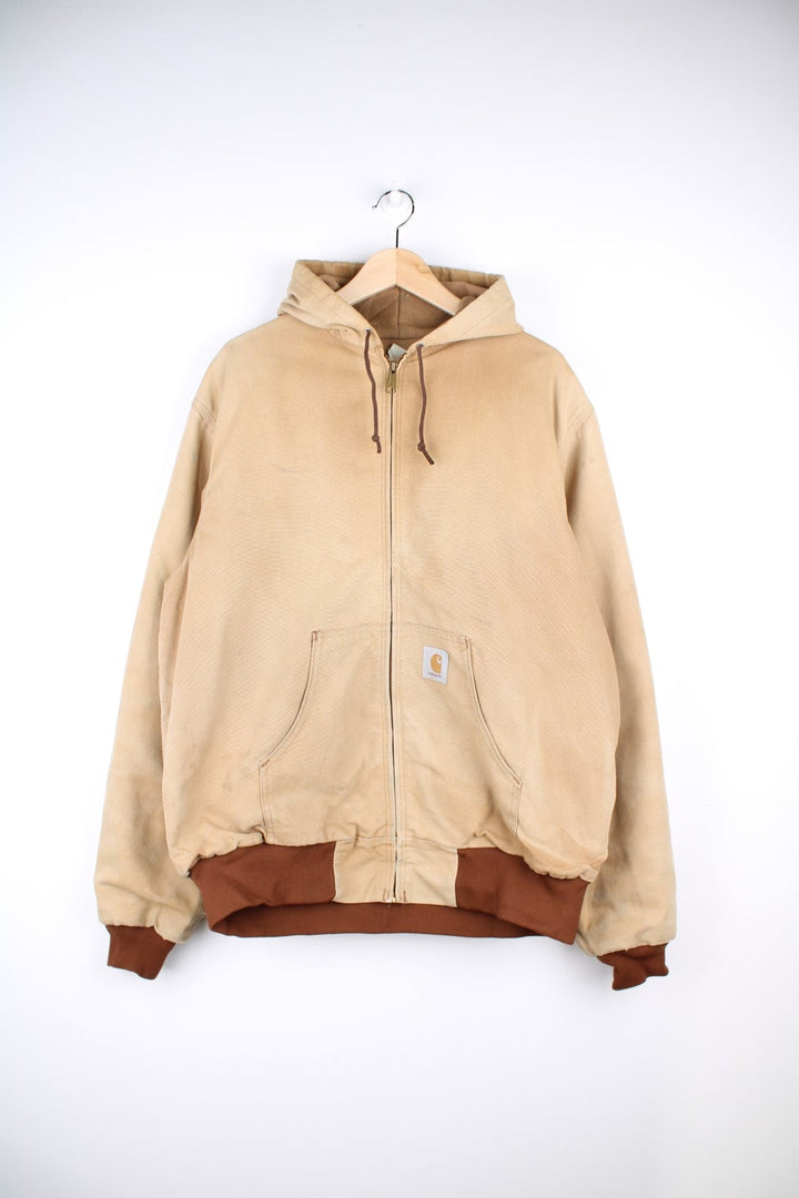 Vintage Carhartt Active Hooded Jacket in a tan colourway. The jacket has two front pockets, a gold zip to close and the Carhartt logo stitched onto the front. 
