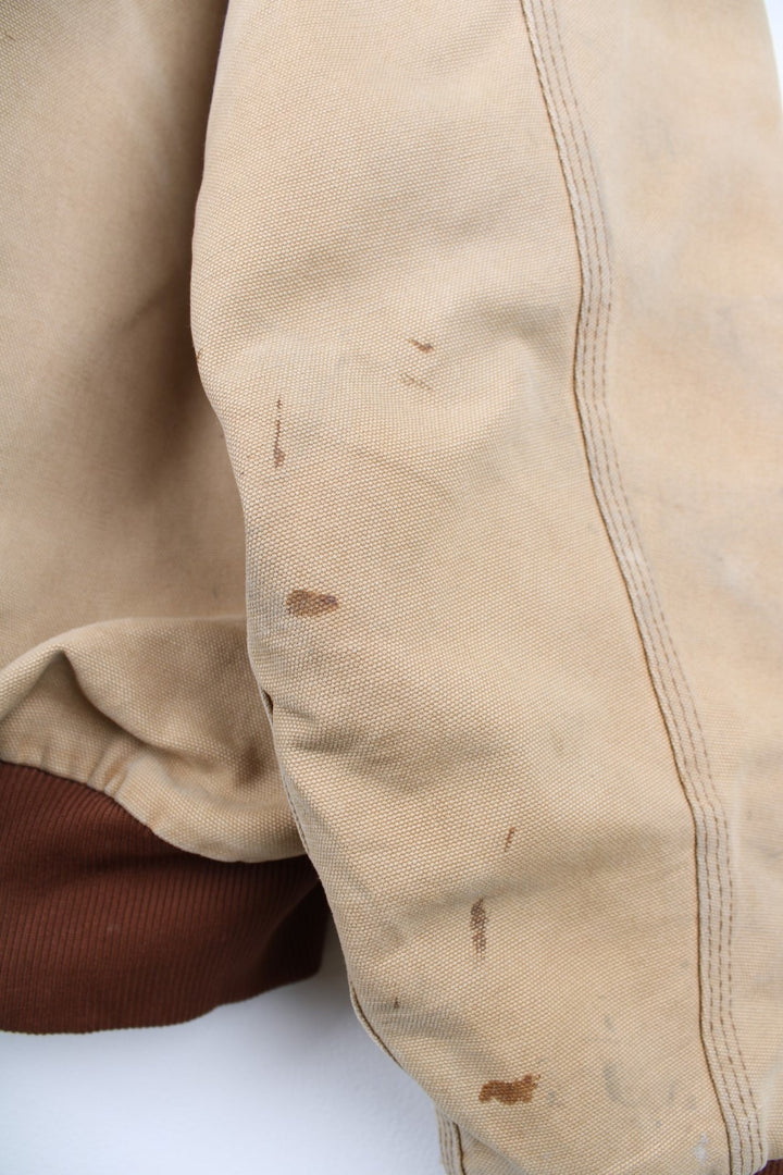 Vintage Carhartt Active Hooded Jacket in a tan colourway. The jacket has two front pockets, a gold zip to close and the Carhartt logo stitched onto the front. 