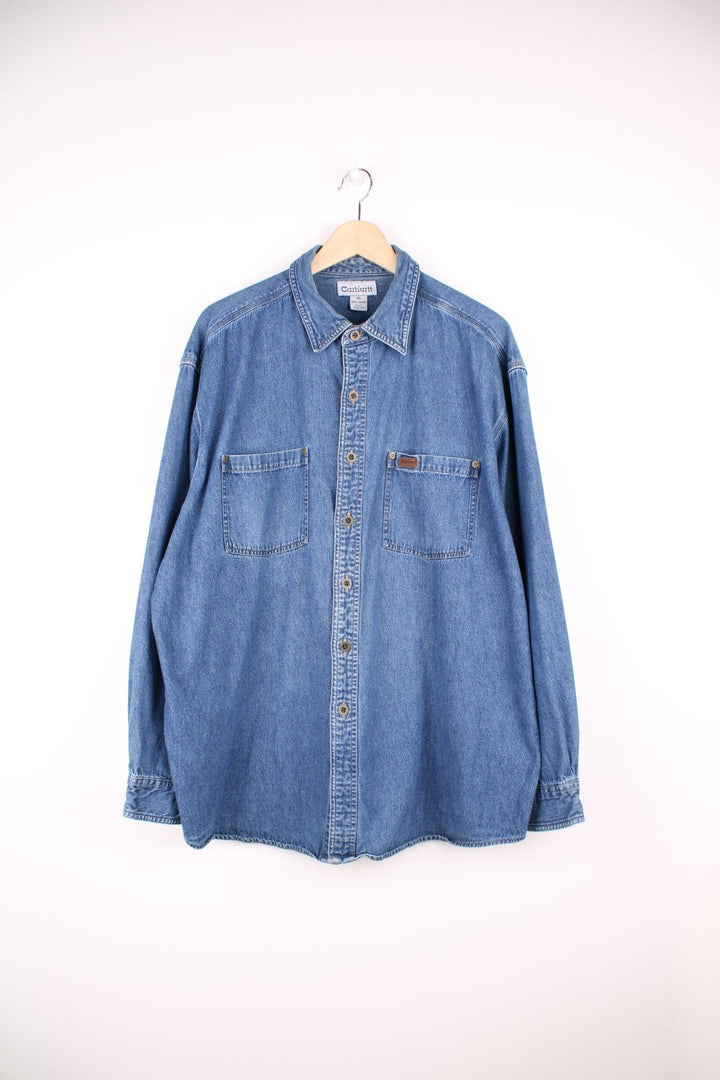 Carhartt button through denim blue denim shirt. Features chest pockets and embroidered leather logo.