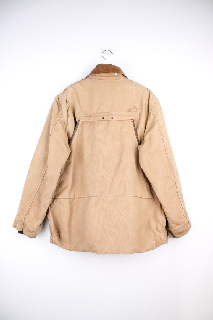  Hunting Jacket in a  browwn colourway with cordurory collar and shoulder pads. Buttons up and has multiple utility pockets including a big detachable pouch pocket on the back, insulated with a blanket lining, and has the logos embroidered on the front.