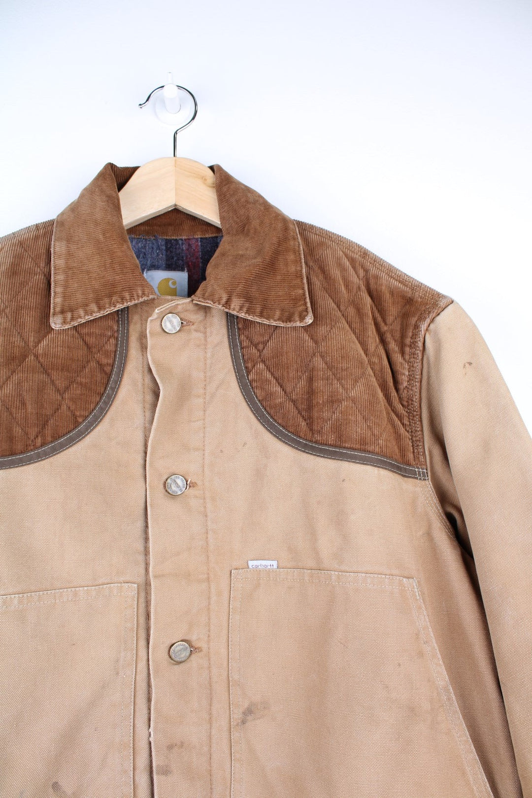  Hunting Jacket in a  browwn colourway with cordurory collar and shoulder pads. Buttons up and has multiple utility pockets including a big detachable pouch pocket on the back, insulated with a blanket lining, and has the logos embroidered on the front.