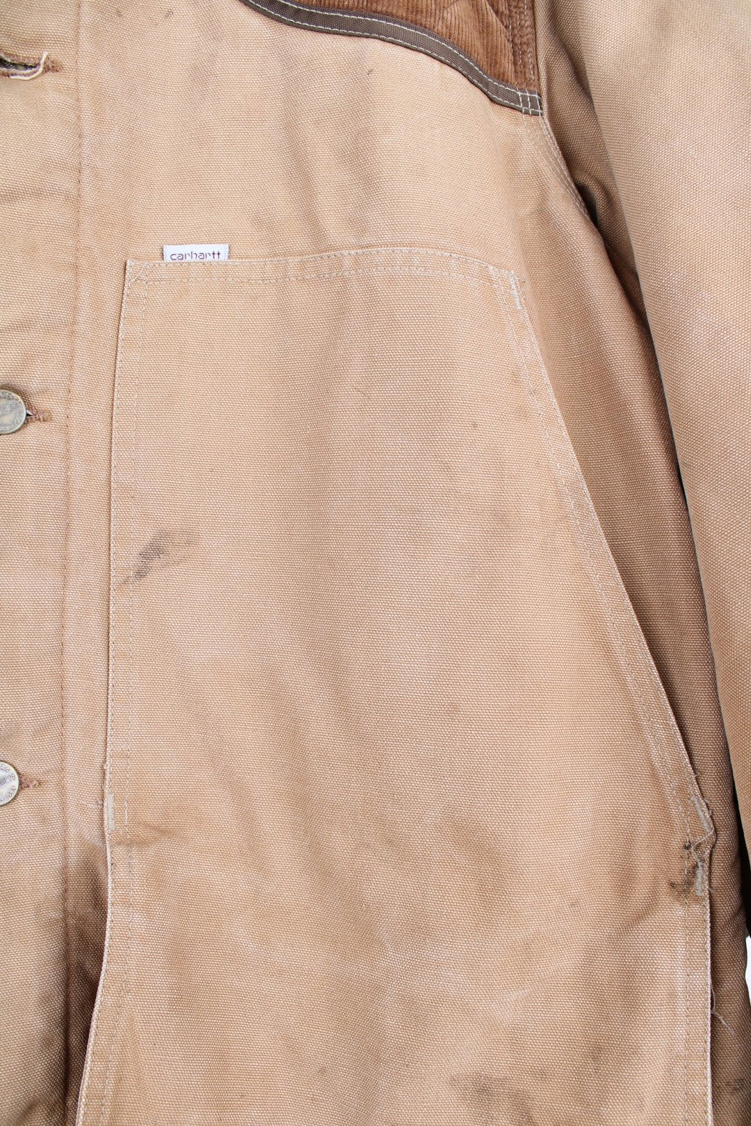  Hunting Jacket in a  browwn colourway with cordurory collar and shoulder pads. Buttons up and has multiple utility pockets including a big detachable pouch pocket on the back, insulated with a blanket lining, and has the logos embroidered on the front.