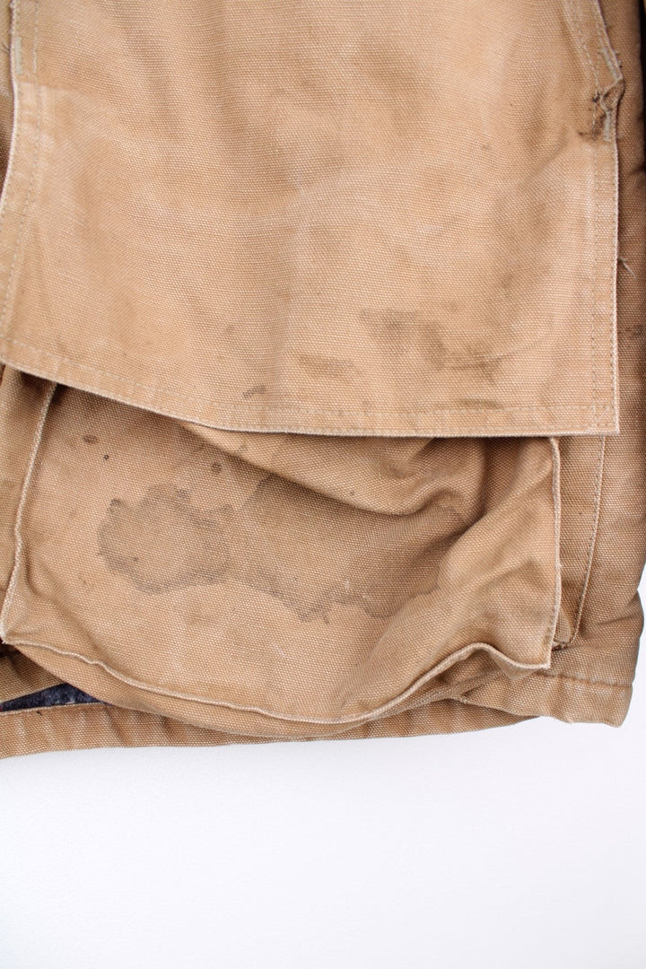 Hunting Jacket in a  browwn colourway with cordurory collar and shoulder pads. Buttons up and has multiple utility pockets including a big detachable pouch pocket on the back, insulated with a blanket lining, and has the logos embroidered on the front.