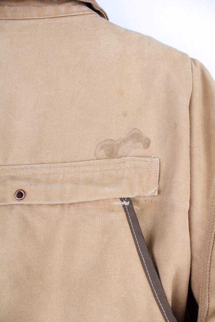  Hunting Jacket in a  browwn colourway with cordurory collar and shoulder pads. Buttons up and has multiple utility pockets including a big detachable pouch pocket on the back, insulated with a blanket lining, and has the logos embroidered on the front.