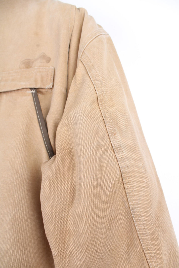  Hunting Jacket in a  browwn colourway with cordurory collar and shoulder pads. Buttons up and has multiple utility pockets including a big detachable pouch pocket on the back, insulated with a blanket lining, and has the logos embroidered on the front.