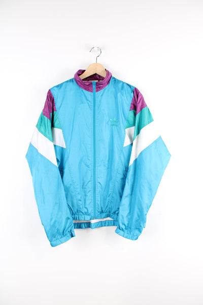 Vintage 90s blue Adidas tracksuit top, features embroidered logo on the chest as well as a white, green and purple panel feature on both arms