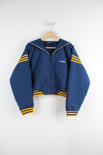 Vintage cropped, quilted jacket with embroidered logo on the chest and yellow stripe detailing. Zip split hood with logo and stitch detailing