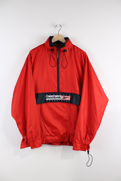 Vintage Reebok red pullover jacket with half zip, embroidered logo, packaway hood and large central pocket.
