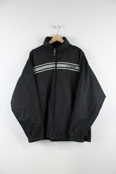 Vintage Reebok black tracksuit jacket with embroidered logo, packaway hood and a grey stripe across the chest and sleeves.