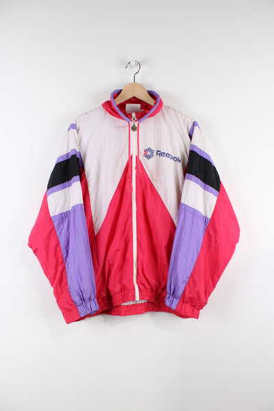 Pink 90s Reebok shell jacket. Features printed logo on the chest.