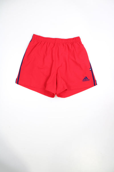 Red Adidas shorts with elasticated waistband and tie waist. Features signature three stripes and embroidered logo.