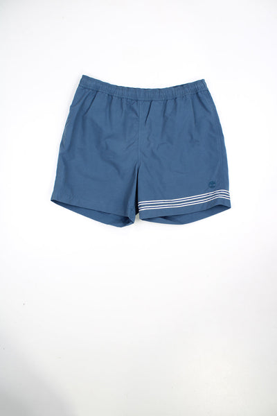 Blue Timberland swim shorts with elasticated waist and drawstring. Features embroidered logo and stripe detail.
