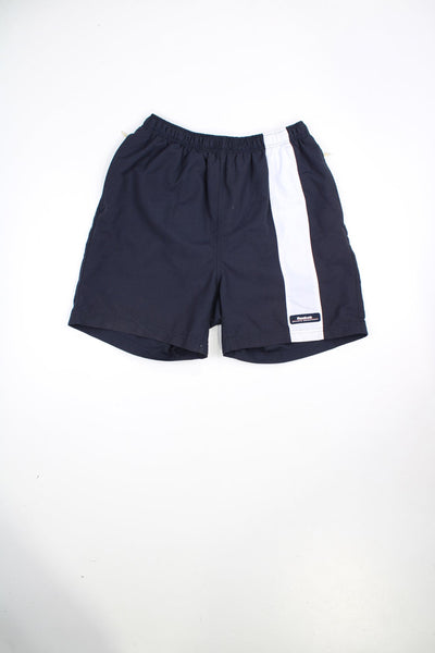 Navy blue Reebok swim shorts with elasticated waist. Features white stripe detail and puff print logo.