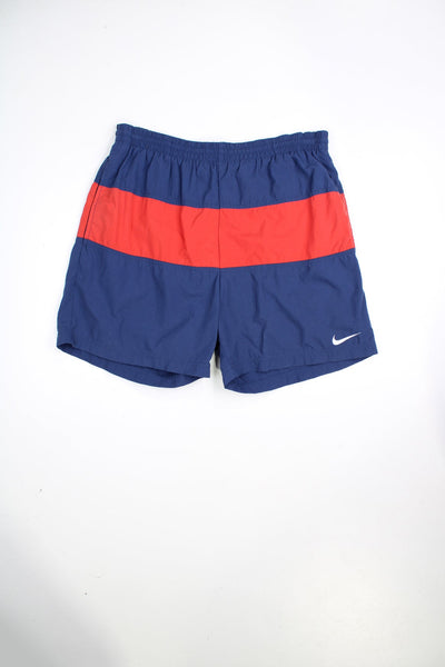 Blue and red vintage Nike swim shorts with elasticated waist and drawstring. Features embroidered logo and printed logo on the back.