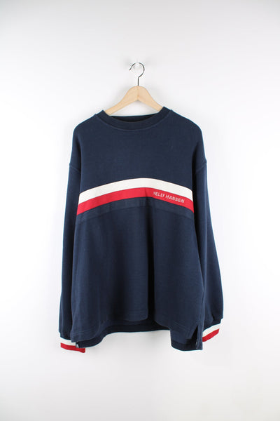 Navy Helly Hansen sweatshirt with white red and blue stripe feature across the chest and cuffs and an embroidered logo.