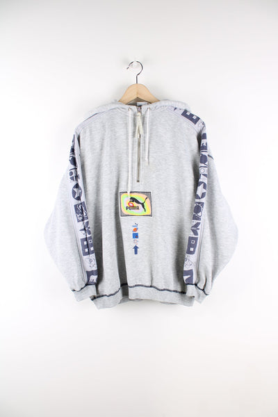 Grey vintage puma hoodie with quarter zip. Features central embroidered logo, graphic print on the back and stripe down each arm with navy print.