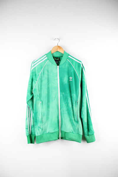 Green Adidas X Pharrell Williams tracksuit top. Features embroidered logo on the chest and signature three stripe detail down each sleeve.