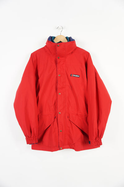 Berghaus red zip through waterproof jacket with removable fleece lining and draw string waist, embroidered logo on the chest and foldaway hood