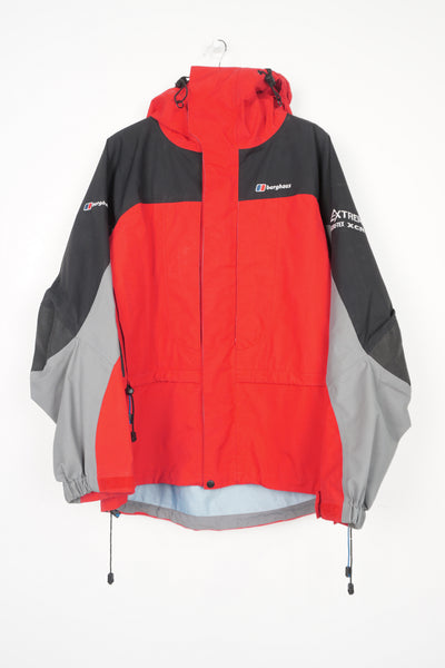 Berghaus red and black zip through waterproof jacket with draw string waist,  embroidered logo on the chest and roll up hood