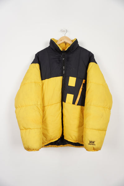 Black and yellow Helly Hansen puffer jacket with multiple pockets, drawstring hem and embroidered spell-out logos on front and back